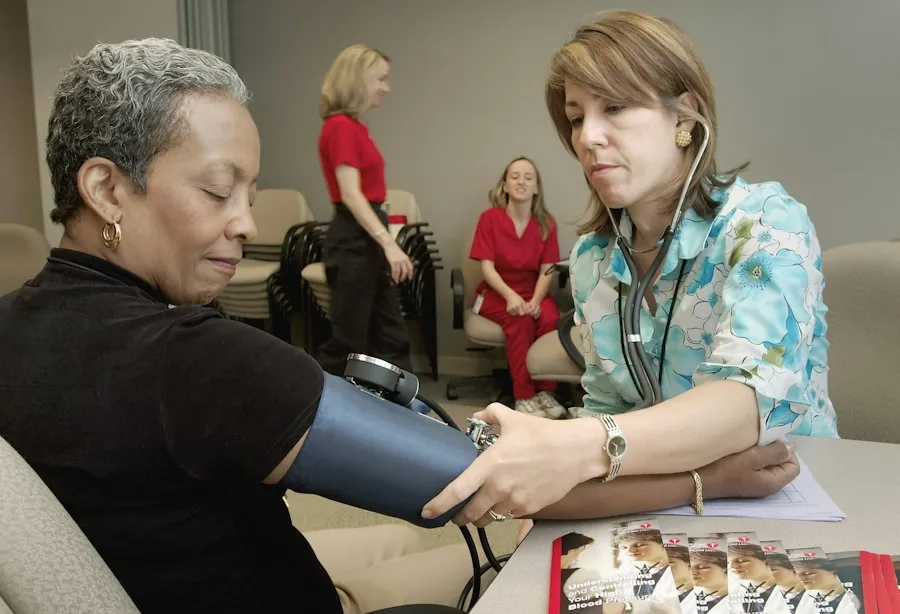 A practice nurse chatting with an older woman while checking her blood pressure
